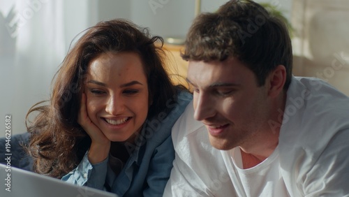 Happy Caucasian couple man woman laughing together at home using laptop computer smiling love technology talking discussing watching movie relationship boyfriend girlfriend sweetheart romantic enjoy