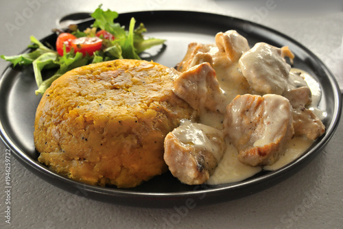 Tableau sur toile Mofongo con pollo en salsa de ajo cremosa acompañado de ensalada fresca, servido en plato tradicional puertorriqueño