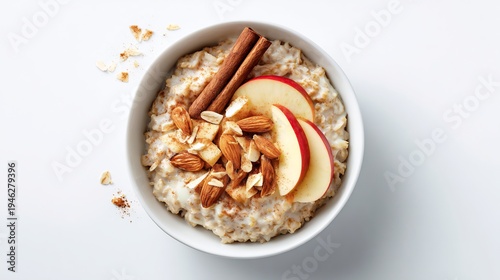 Hearty oatmeal breakfast with sliced apples, almonds, and cinnamon sticks, top-down view