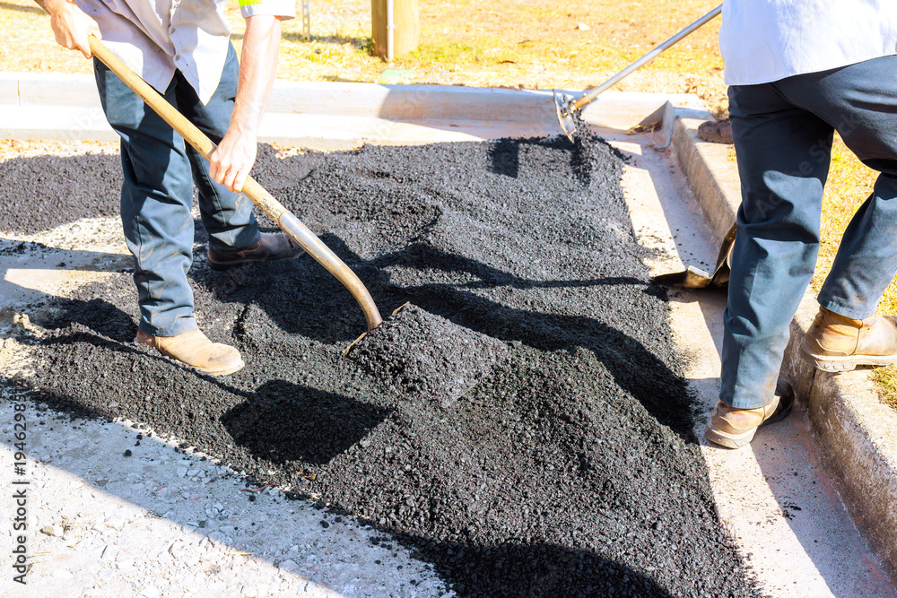 Fototapeta premium Workers lay down asphalt in parking lot