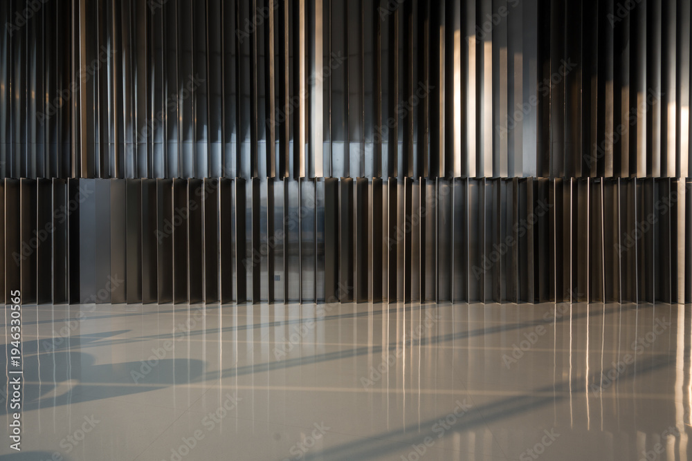 Fototapeta premium Metallic vertical striped wall with light and shadow reflections on a polished floor surface