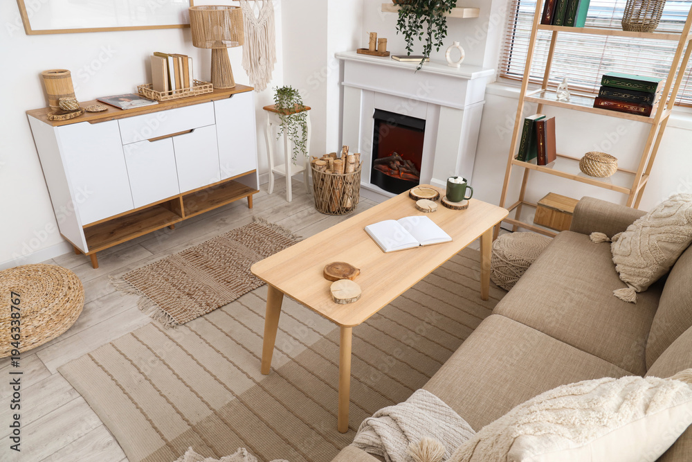 Naklejka premium Interior of living room with sofa, shelving unit, coffee table, fireplace, commode and firewood in wicker basket, top view