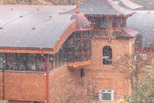 Large flakes of snow against the backdrop of a country house
