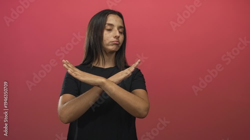 Young hispanic woman arms crossed x with pouting lips and closed eyes in pink studio; rejection assertiveness boundary.