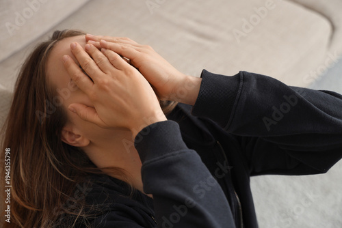 Sad young woman near sofa a...