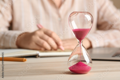 Hourglass near woman workin...