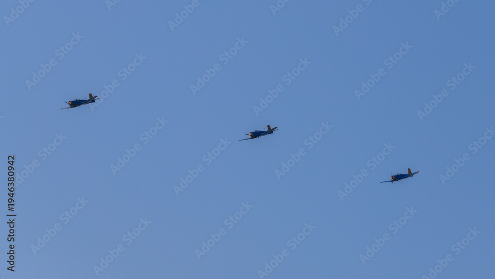 Fototapeta premium Three propeller aircraft flying in formation against a bright clear sky during an aerial aviation display