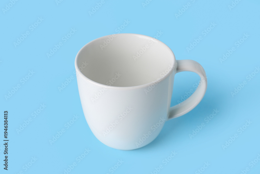 Fototapeta premium White empty ceramic mug on blue background