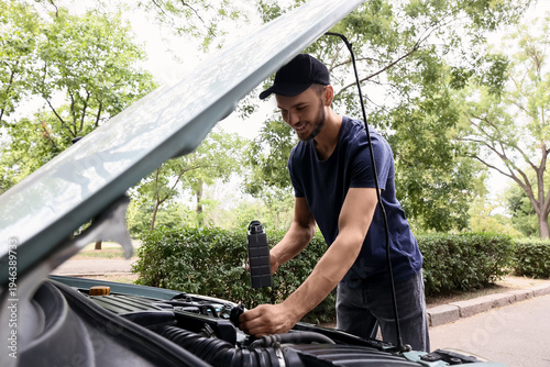 Male mechanic refilling car...