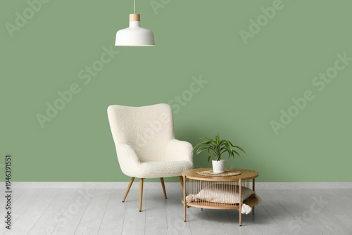 Stylish living room with white armchair, coffee table, houseplant and white hanging lamp