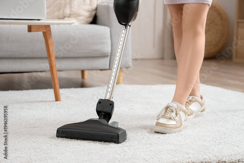 Young woman cleaning carpet...