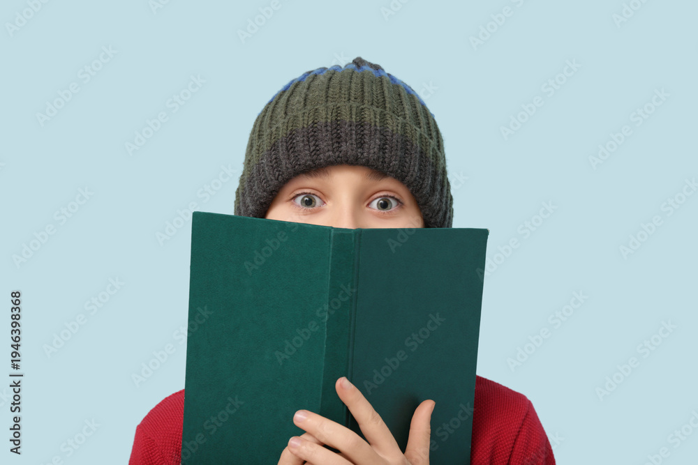 Fototapeta premium Cute little boy with book on blue background
