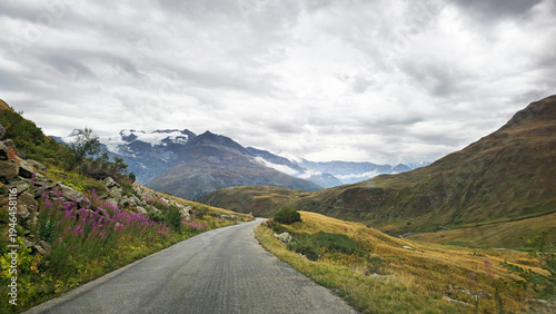 Fotografie Winding mountain road Route du Col de l’Iseran traversing a high-altitude Alpine landscape, Savoie, France, Europe
