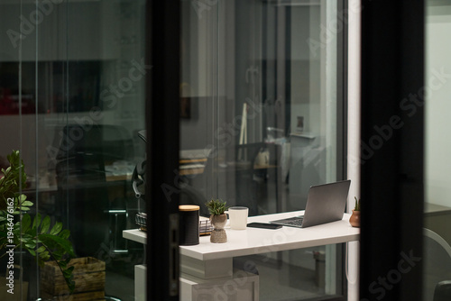 Foto Modern office workspace featuring open laptop, coffee mug, small potted plants a