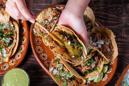 Fotografie Close-up of tacos al pastor, prepared with fresh ingredients and green sauce on a wooden background