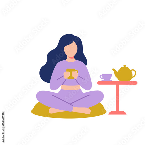 Woman sits cross-legged on a mat drinking tea from a mug