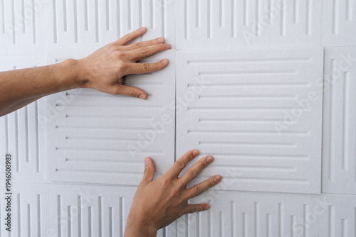 Φωτογραφία Close-up hand of handyman applying white soundproof acoustic panels onto a wall,