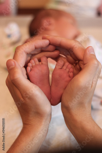 Father holding newborn baby feet in hands, close-up family moment