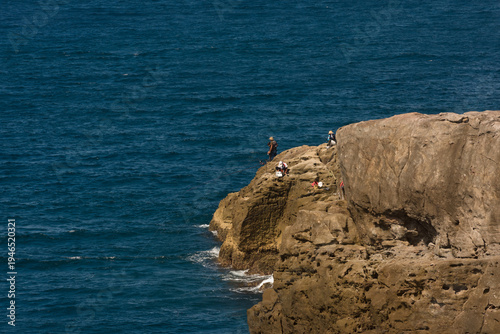 Wallpaper Mural Group of people fishing on a steep rocky cliff by the deep blue ocean on a sunny day Torontodigital.ca