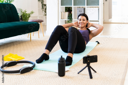 Young woman doing crunches with hands behind head while lying down at home