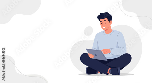 Young man sitting cross-legged, smiling and using a tablet computer, minimalist background