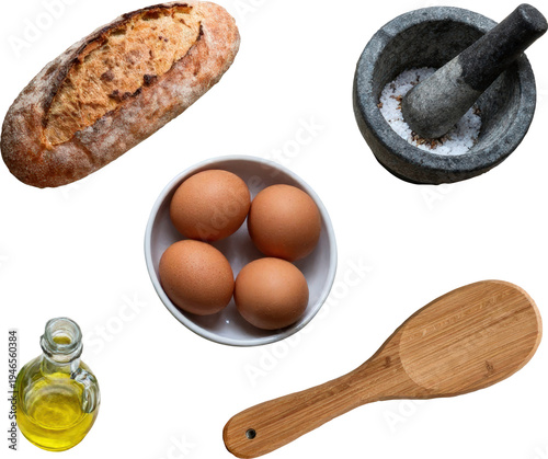 
Freshly baked rustic bread loaf, raw brown eggs in a bowl, bottle of oil, wooden spoon and stone mortar and pestle isolated on white background. Cooking and baking ingredients concept.

