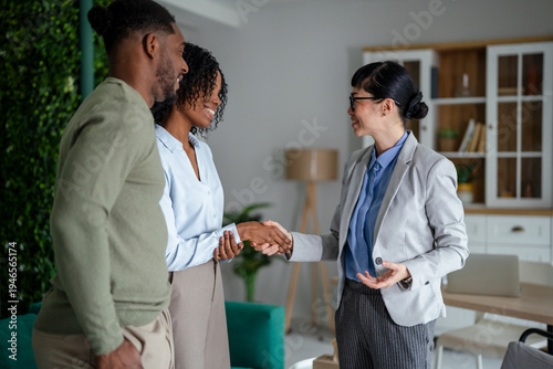 Obraz na plátne Real estate agent shaking hands with diverse couple
