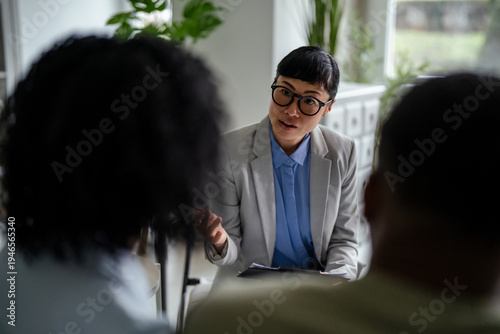 Woman psychologist counseling young couple during therapy session