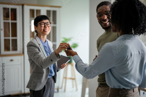 Fotografija Realtor handing over keys to happy couple buying home