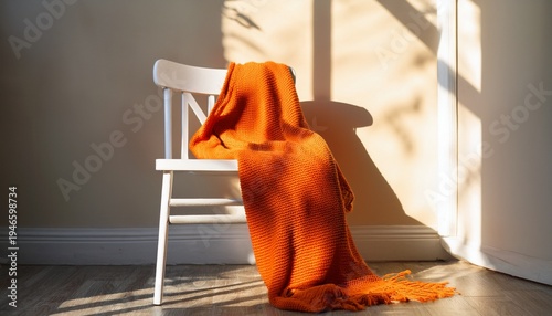 cozy orange blanket draped on a white chair by sunlight