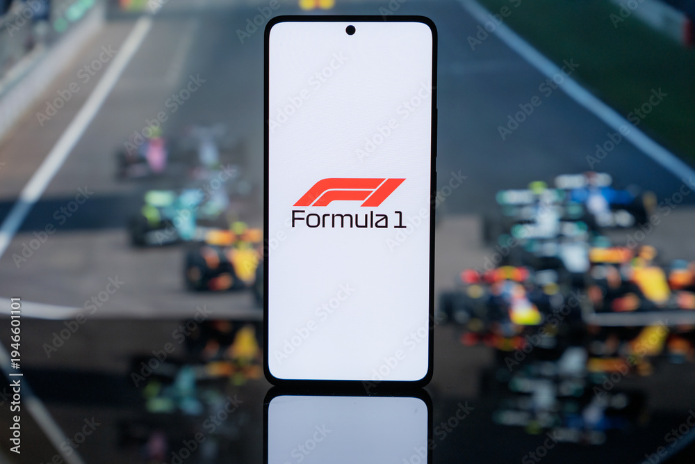 Fototapeta premium the official Formula 1 logo on a white screen, set against a blurred background of F1 racing cars on a track, representing professional motorsport media and digital broadcast coverage