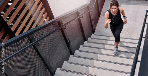 Fotografie Fitness, running and woman on stairs with earphones, cardio exercise or music playlist in physical activity