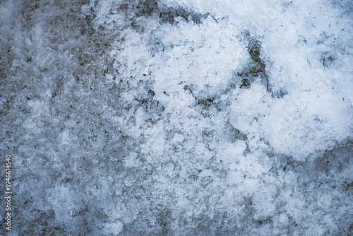 The layered structure of a snowfield and glacier lying on the bank of a mountain river in the Tien Shan Mountains of the Pamirs in Tajikistan. The texture of the snow layer lies and melts