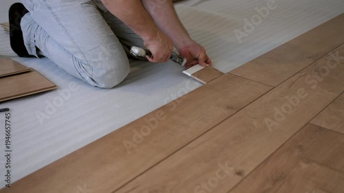 Worker aligning and clicking laminate floor panels together. Interior renovation and flooring installation process.