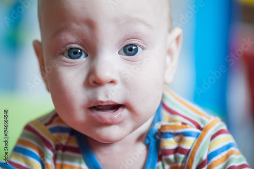 Photography In a soft, colorful environment, a curious baby gazes with bright blue eyes, capturing the essence of innocence and wonder