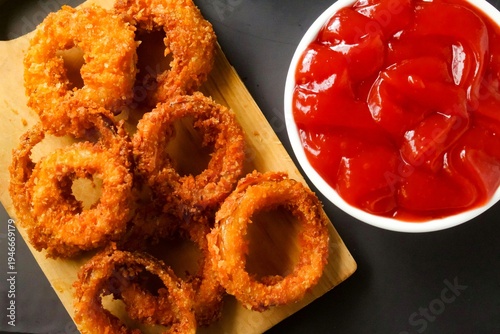 top view of onion rings on a cutting board on a black background