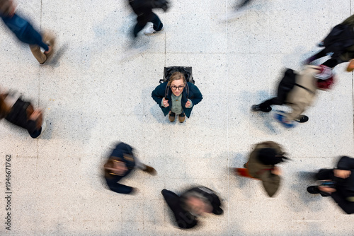 Commuter woman with backpack standing still amid rushing crowd overhead