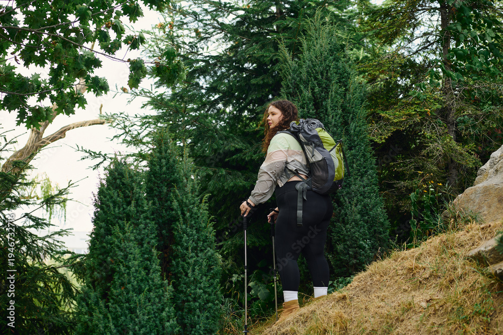 Fototapeta premium Young woman explores green mountains on an adventurous hiking journey in nature