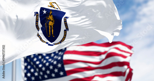 The flags of Massachusetts and the United States waving in the wind on a clear day