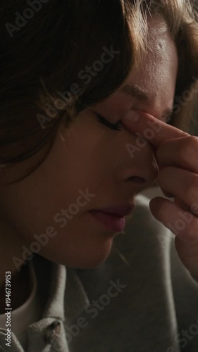 Vertical close up shot of sad Caucasian gen Z woman rubbing eyes while feeling drowsy after sleepless night at home