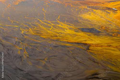 Aerial view of stark, contrasting textures paint the landscape with veins of bright yellow cutting through the muted earth tones, creating a surreal and captivating scene, Iceland.