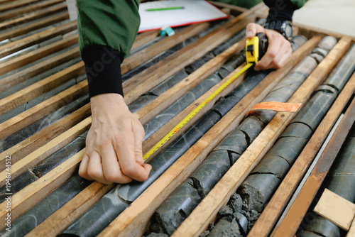 Fotografie Measuring geological core samples with tape measure in industrial setting