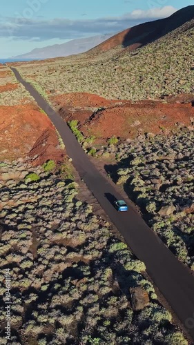 Wallpaper Mural Blue car driving on a lonely road through lava fields, vertical drone shot of El Hierro island. Aerial perspective of a vehicle on El Hierro island road Torontodigital.ca