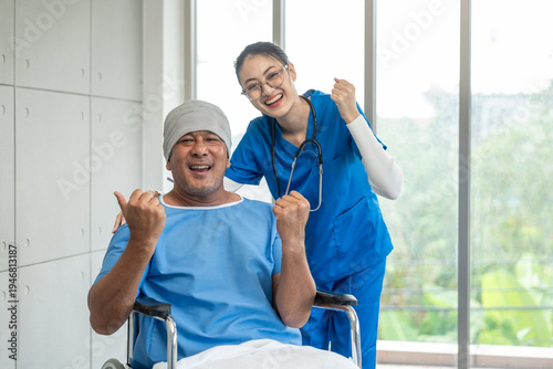 Fotografie A male cancer patient in a wheelchair receives IV therapy while a female doctor