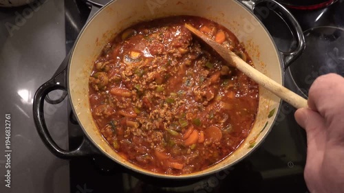Stockholm, Sweden A cook stirs a Bolognese meat sauce with a wooden spoon. 
