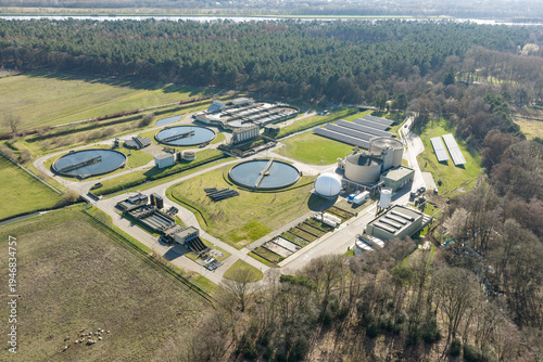 Drone aerial view of municipal wastewater treatment facility with clarifier basins in rural landscape
