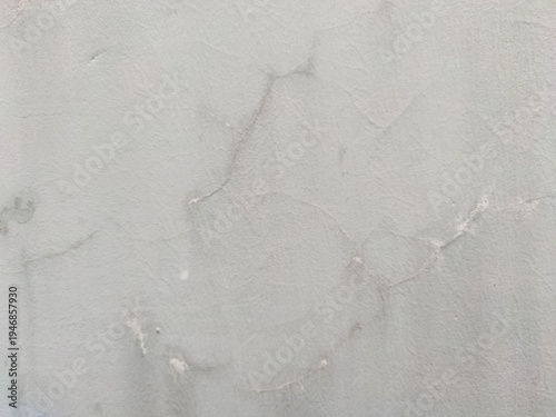 Photos A light grey concrete wall texture featuring subtle hairline cracks and weathered surface details
