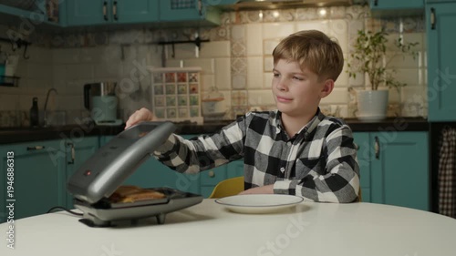Young boy preparing a sandwich using a sandwich maker at home, enjoying a simple cooking activity in a cozy kitchen setting