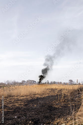 Scorched field with fire burning in the distance during heatwave