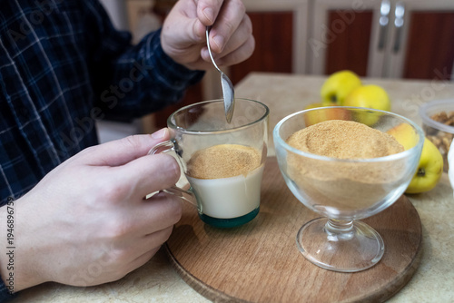 Wallpaper Mural Person adding apple fiber powder to a glass of yogurt, surrounded by fresh apples and walnuts. Healthy prebiotic supplement for gut health, digestion and weight management. Torontodigital.ca
